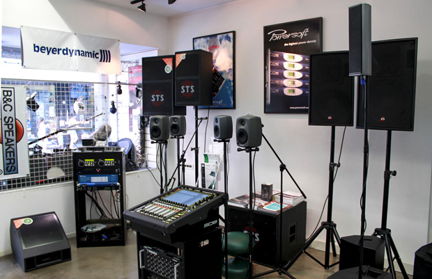 Showroom with STS loudspeakers, studio monitors, a digital mixer and a Powersoft poster on the wall