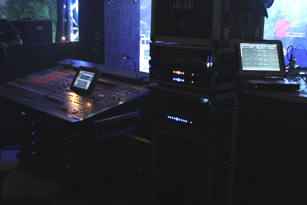 Front-of-house position with a mixing console, equipment racks and a tablet showing control software