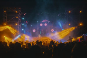 Les Dunes Electroniques stage at night, with orange and blue light beams above the crowd