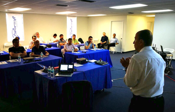 A speaker addresses Latin American distributors seated at tables, with Powersoft banners