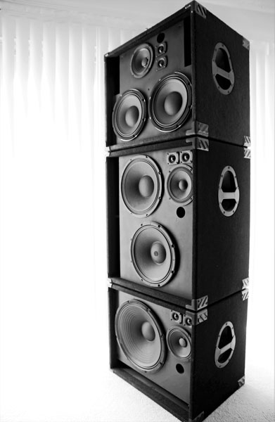 Three stacked speaker cabinets with woofers and tweeters, black and white photo